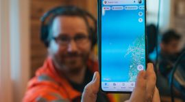 Mann holder opp en mobiltelefon med kart.