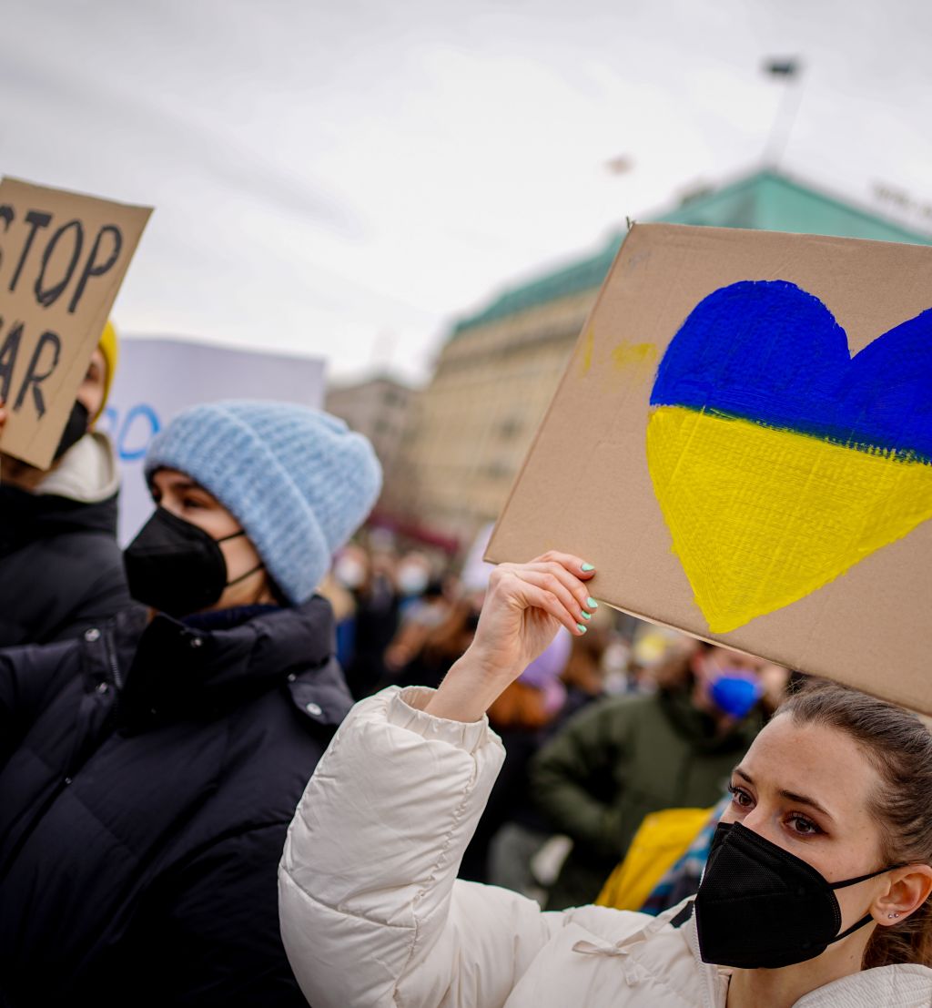 kvinne holder opp en plakat under en demonstrasjon med et hjerte med de ukrainske fargene