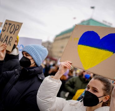 kvinne holder opp en plakat under en demonstrasjon med et hjerte med de ukrainske fargene