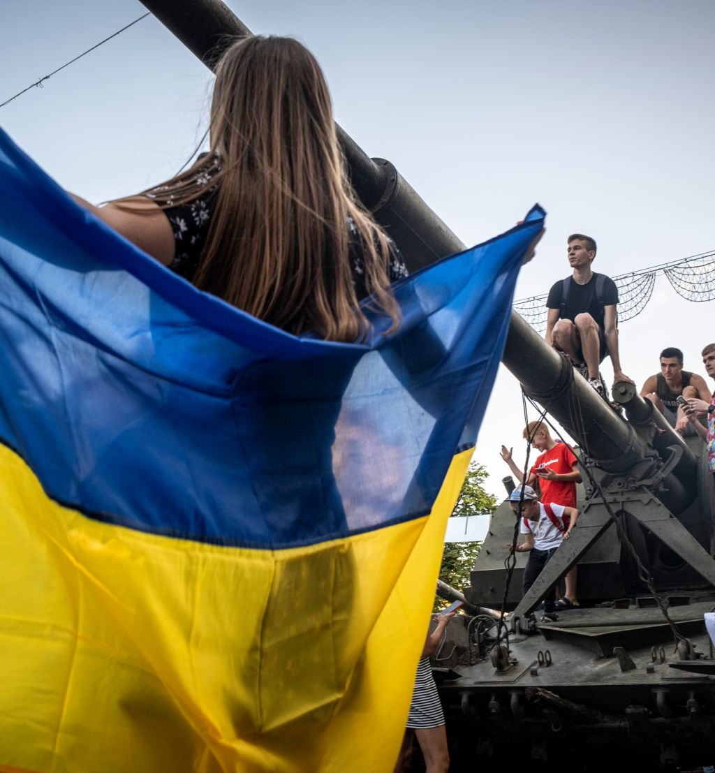 Jente holder Ukrainsk flagg. Unger og tenåringer klatrer på en beslaglagt Russisk stridsvogn som er utstilt på gaten i Kiev.