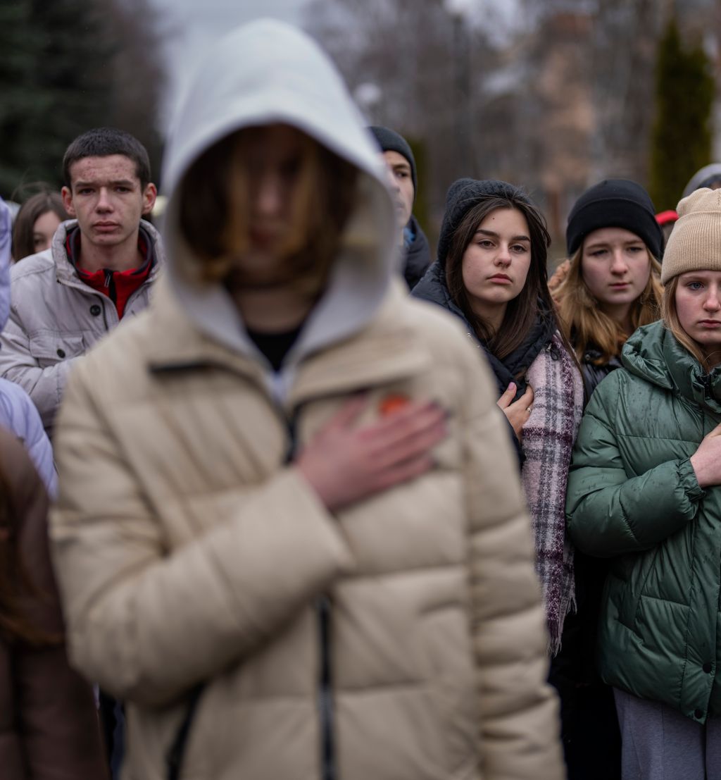 Sørgende ungdommer holder hånden til hjertet mens den Ukrainske nasjonalsangen spilles i en begravelse.