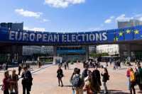 mennesker på et torg foran et stort banner der det står European elections