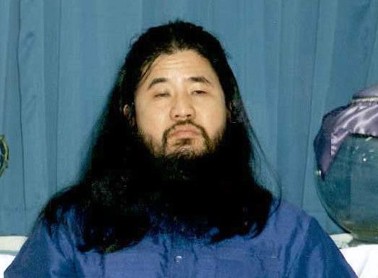 Shoko Ashara - japansk terrorist med svart hår og mye skjegg. Han har på seg en blå bluse.