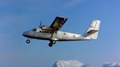 En sølvfarget Dehavilland Twin Otter i Nord Norge 1978 flyr med fjell i bakgrunnen.