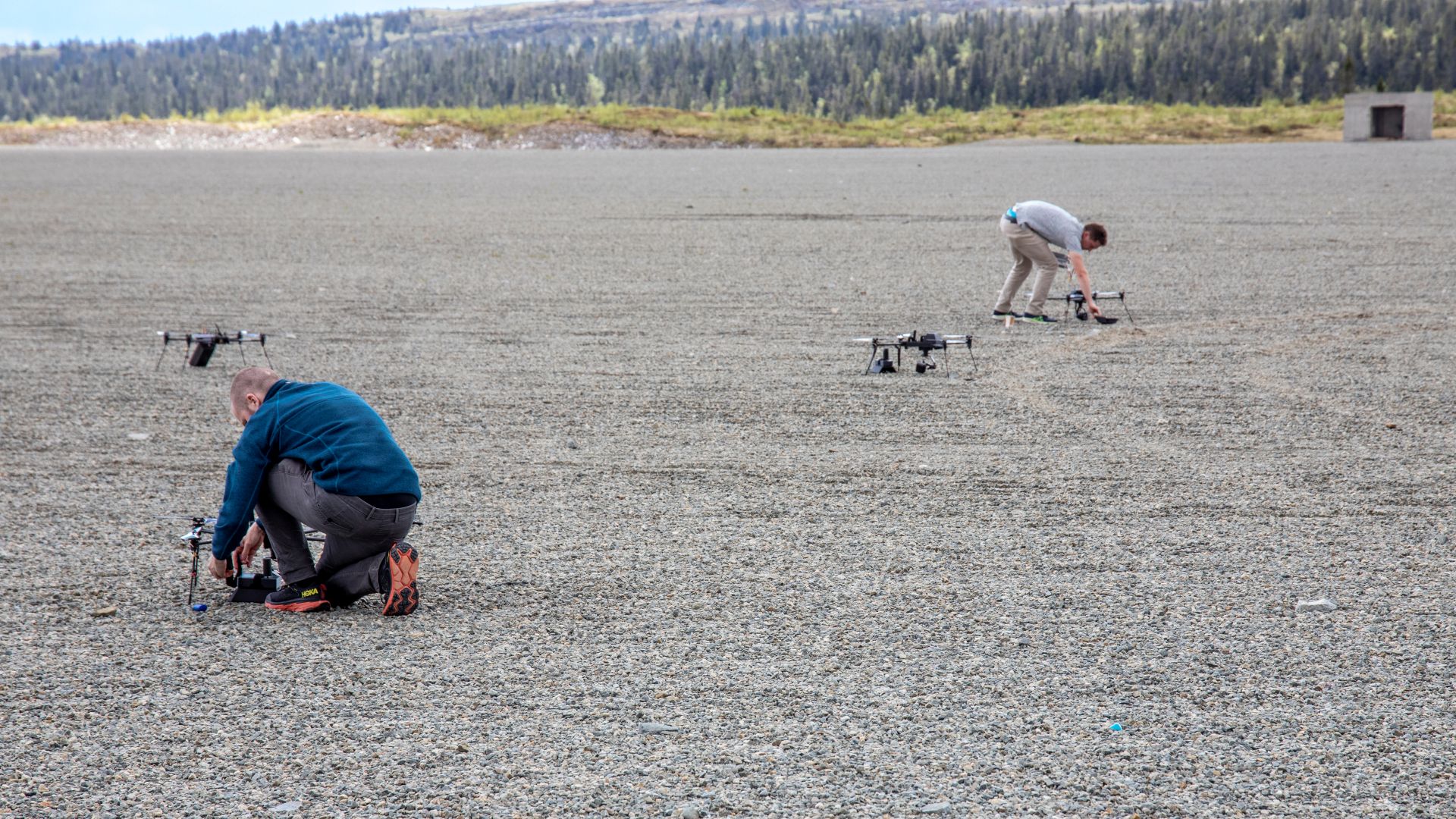 to forskere plasserer små droner ut på grusplass