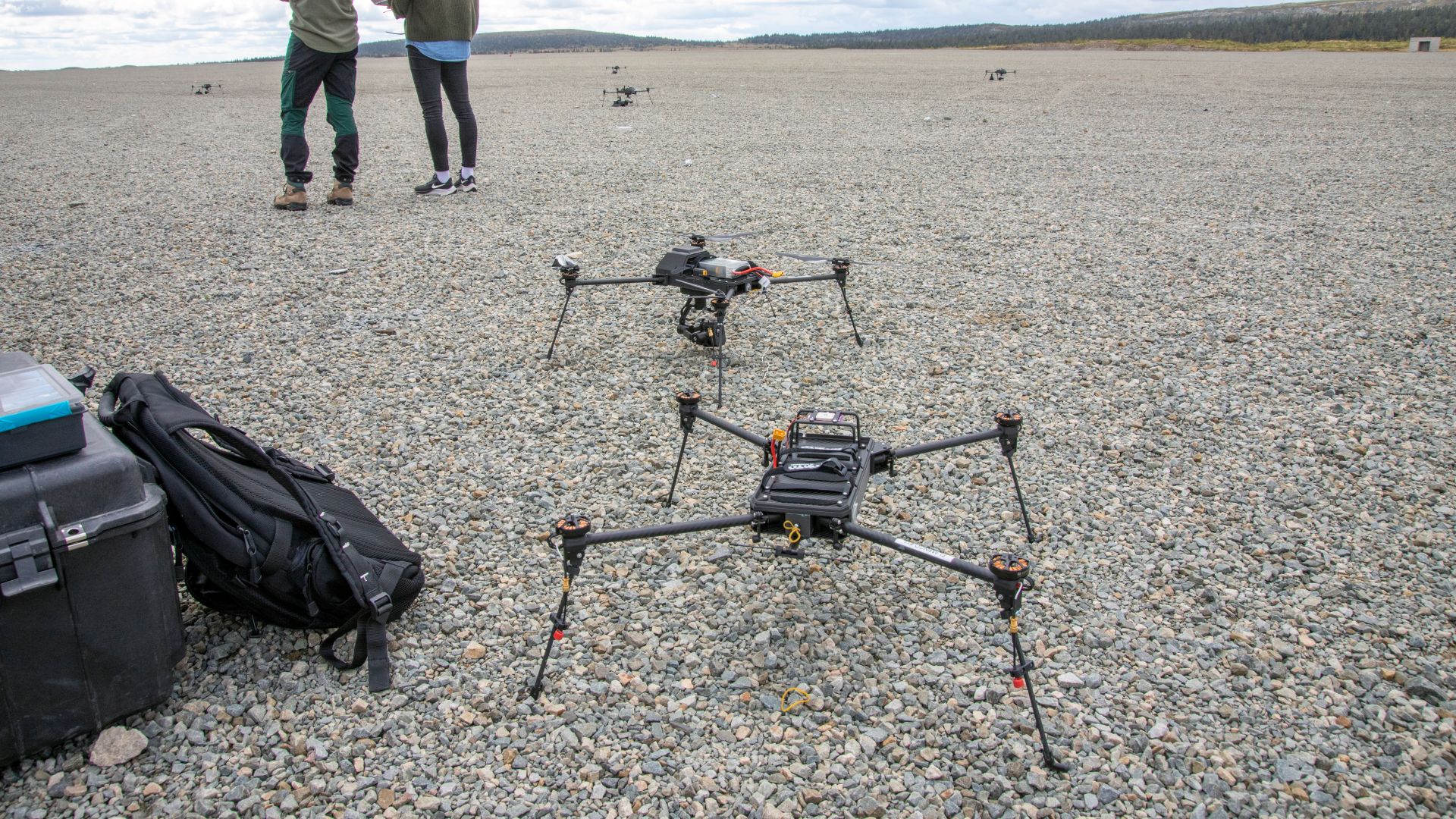 To droner stor på grusen. Bak står to mennesker med ryggen til