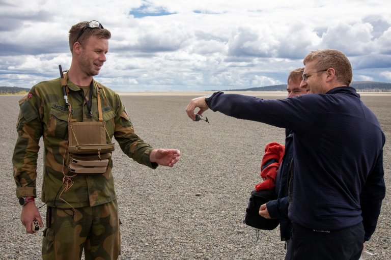Grønnkledd soldat får overrakt liten drone fra sivilist