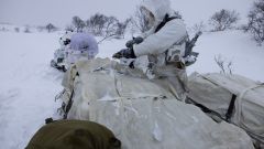 Bilde fra Halkavarre skytefelt i Finnmark. Snøføyk. Soldater er delvis skjult bak en bakketopp.