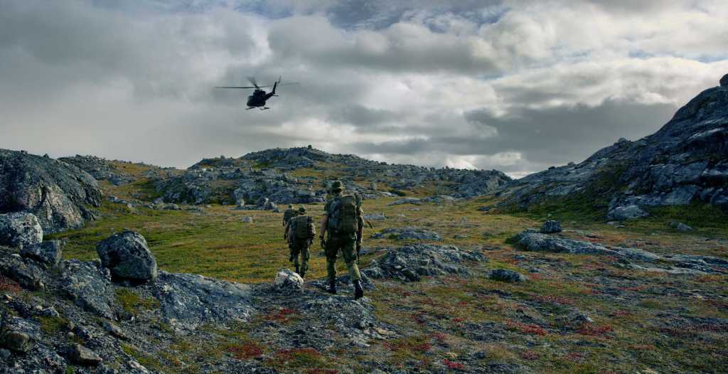 Grensejegere på patrulje med et helikopter i bakgrunnen.