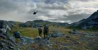 Grensejegere på patrulje med et helikopter i bakgrunnen.