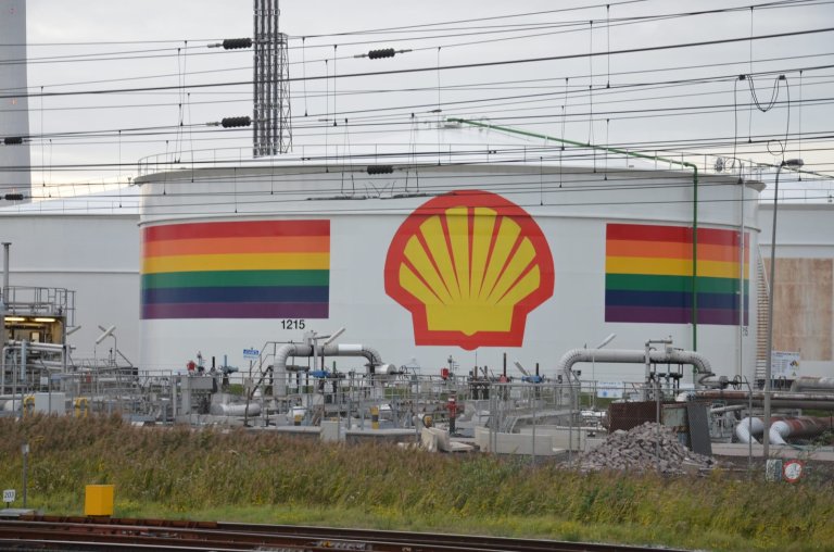 Oljerafineri med logoen til Shell og to regnbueflagg på sidene.
