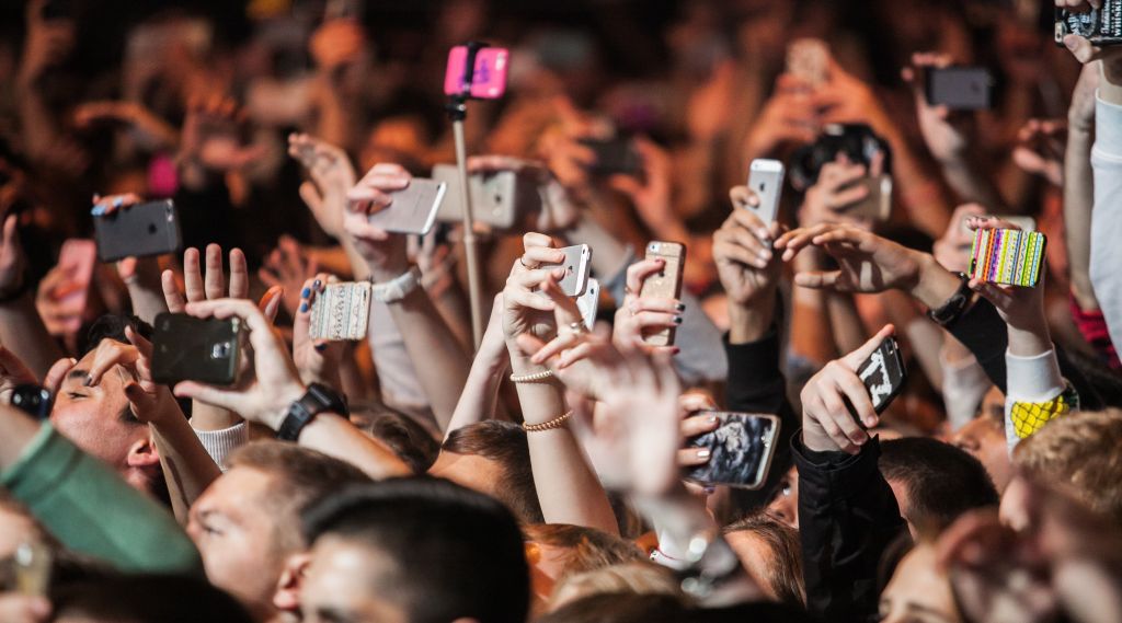 Unge mennesker med smarttelefoner på konsert