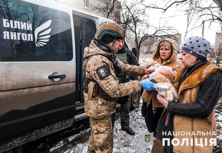 En soldat deler ut brød til do damer.
