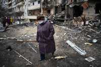 TOPSHOT - A woman walks in front of a damaged residential building at Koshytsa Street, a suburb of the Ukrainian capital Kyiv, where a military shell allegedly hit, on February 25, 2022. - Russian forces reached the outskirts of Kyiv on Friday as Ukrainian President Volodymyr Zelensky said the invading troops were targeting civilians and explosions could be heard in the besieged capital. Pre-dawn blasts in Kyiv set off a second day of violence after Russian President Vladimir Putin defied Western warnings to unleash a full-scale ground invasion and air assault on Thursday that quickly claimed dozens of lives and displaced at least 100,000 people. (Photo by Daniel LEAL / AFP)