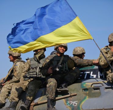 Soldater sitter på tanks med ukrainsk flagg. Foto