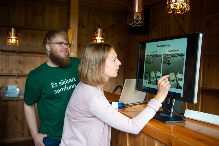 Forsknings- og høyere utdanningsminister Iselin Nybø ser på en dataskjerm med student fra FFI.
