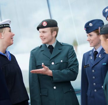 6 unge soldater står i gruppe og snakker og smiler