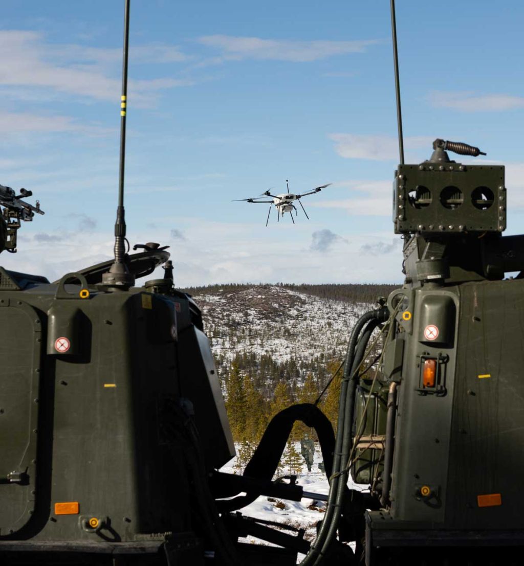 En soldat på et kjøretøy sikter på en drone med et våpen.