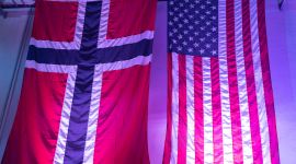 Det norske og amerikanske flagget henges side om side inne i en hall.