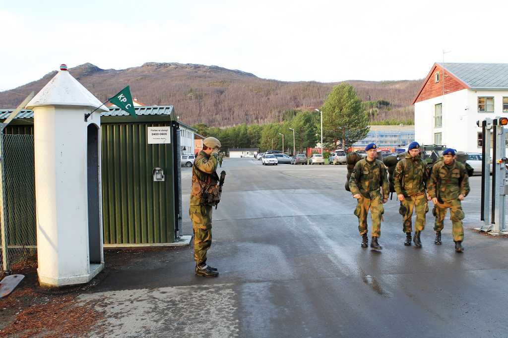 En vakt hilser tre soldater på vei ut fra Maukstadmoen leir.