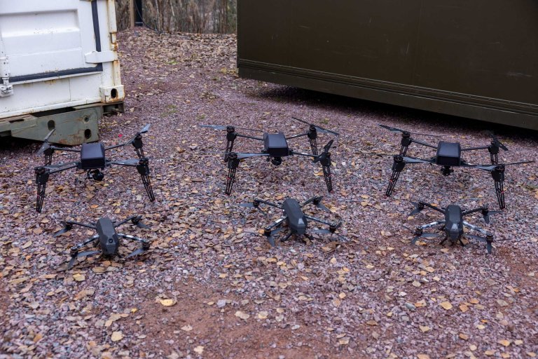 Sorte droner står på bakken. Disse er en del av en dronesverm.