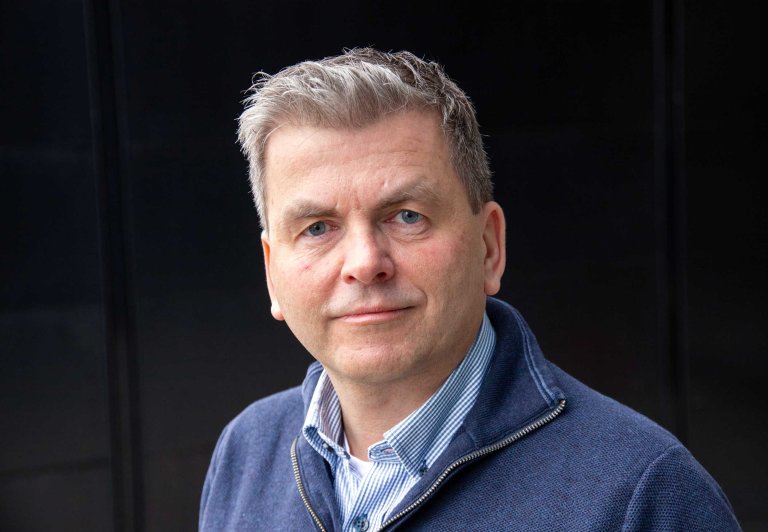 Portrett av Stig Rune Sellevåg i blå genser og skjorte.