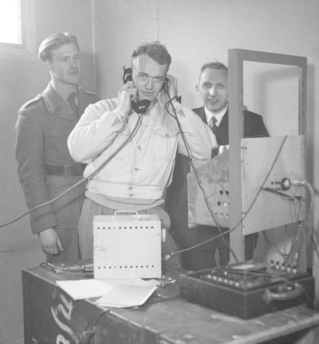 Fra utviklingen av et telesamband. Tre forskere bak en radio.