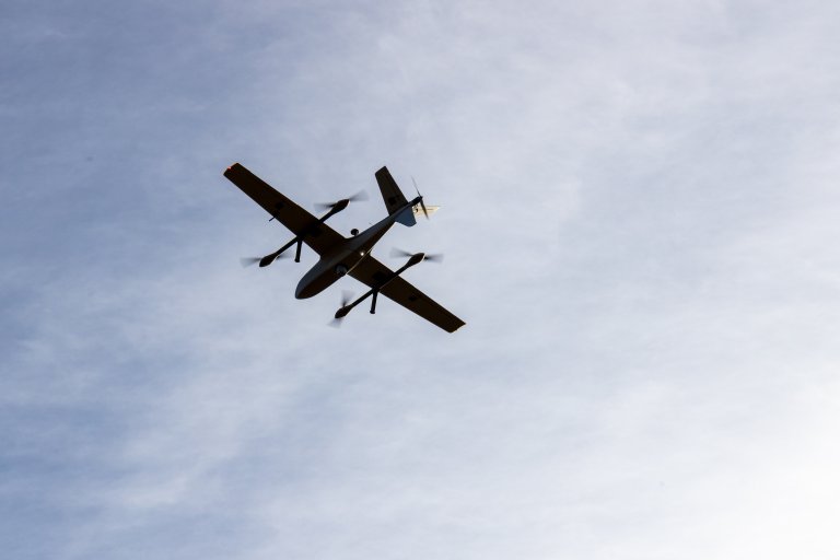 Drone flyr. Fotografert fra bakken. Blå himmel og skyer i bakgrunnen.