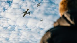 En person ser opp på tre droner som flyr forbi.