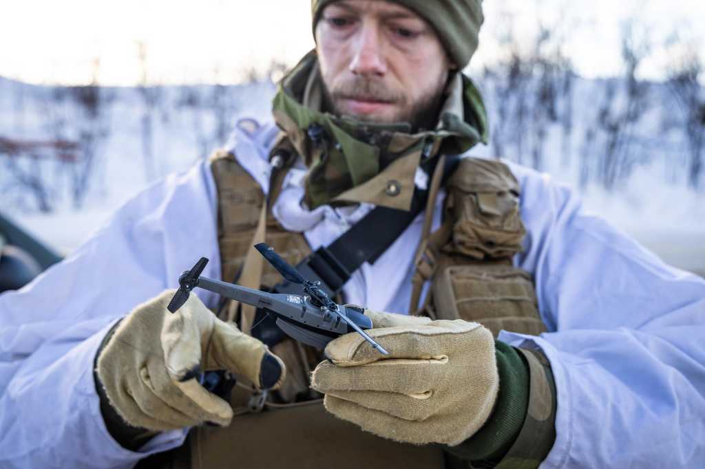 Soldat i vinteruniform som holder en drone, en Black Hornet 3.