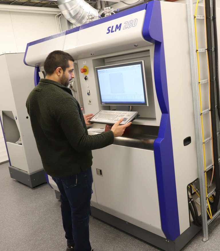 En mann betjener en metall-3D-printer ved FFI.