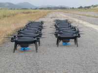 Mange droner oppstilt på bakken. Foto