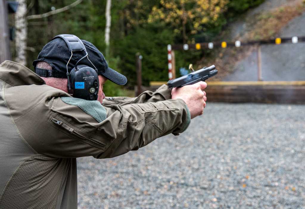 Man med hørselvern avfyrer pistol på skytebane
