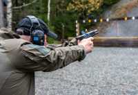 Man med hørselvern avfyrer pistol på skytebane