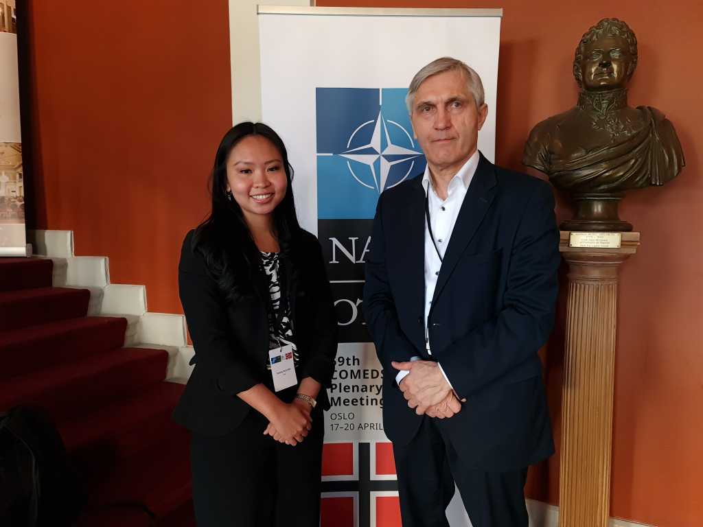 masterstudent og sjefsforsker Engy poserer foran en Nato-logo