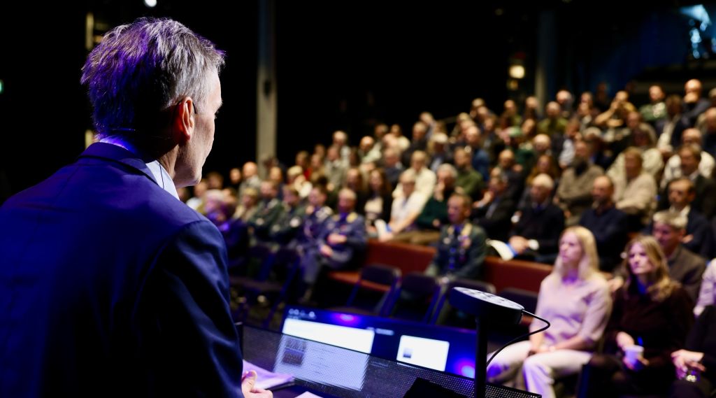 Forskningsdirektør Espen Skjelland på talarstolen framfor ein fullsett Deichmansal i Bjørvika i Oslo.