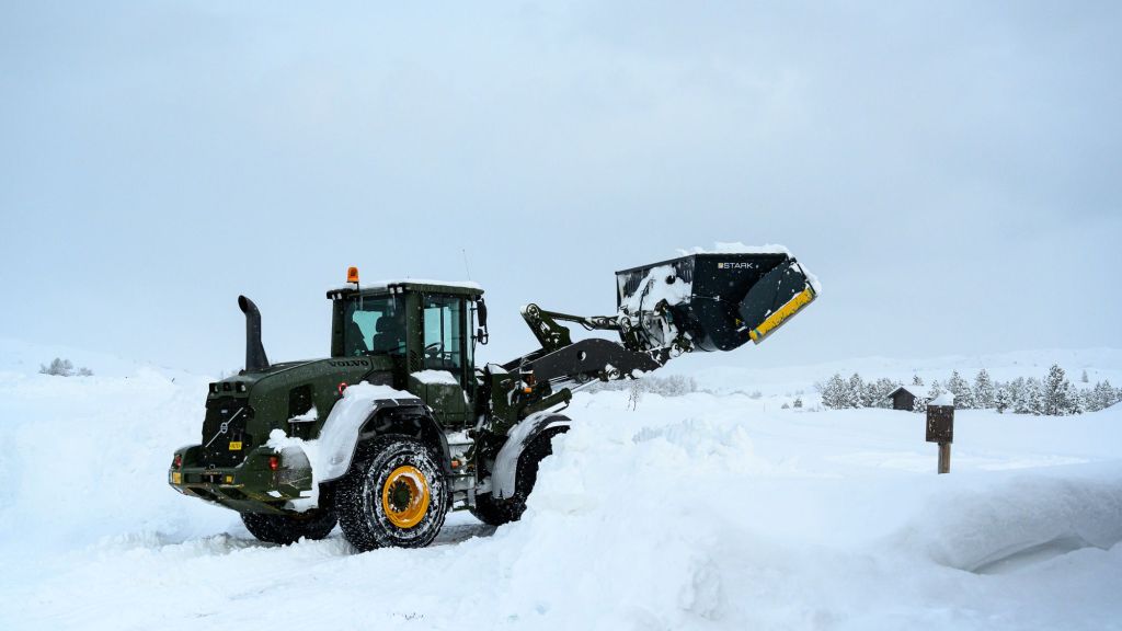 En gravemaskin lager en stor snøfonn