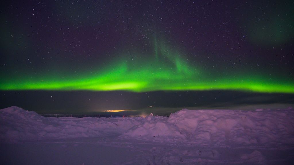 Vakkert nordlys i grønne toner over et snødekt Kirkenes