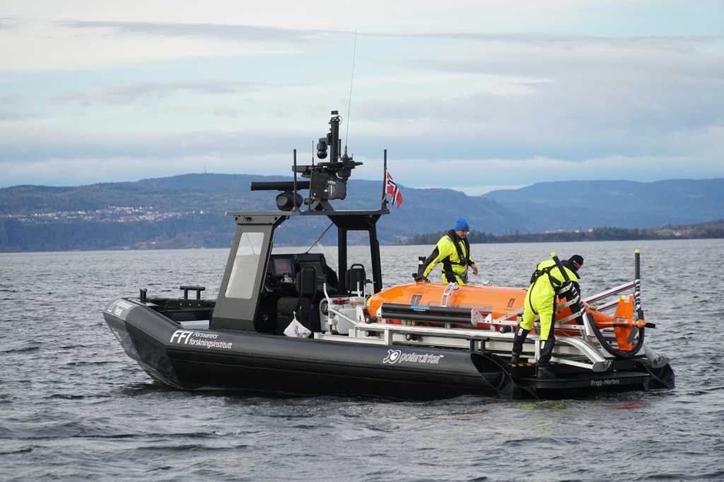 Hugin ombord på båten Frigg. Hugin er orange, mens båten er svart.