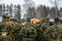 En gruppe soldater står oppstilt med ryggen til kamera. I midten ser vi en kvinnelig soldat med flette.