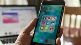 Hånd holder mobil med synlige sociale medier-ikoner