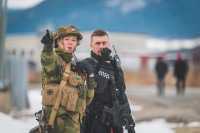 En kvinne i hærens uniform står ved siden av en politimann i uniform. Hun peker mot noe og begge ser i den retningen