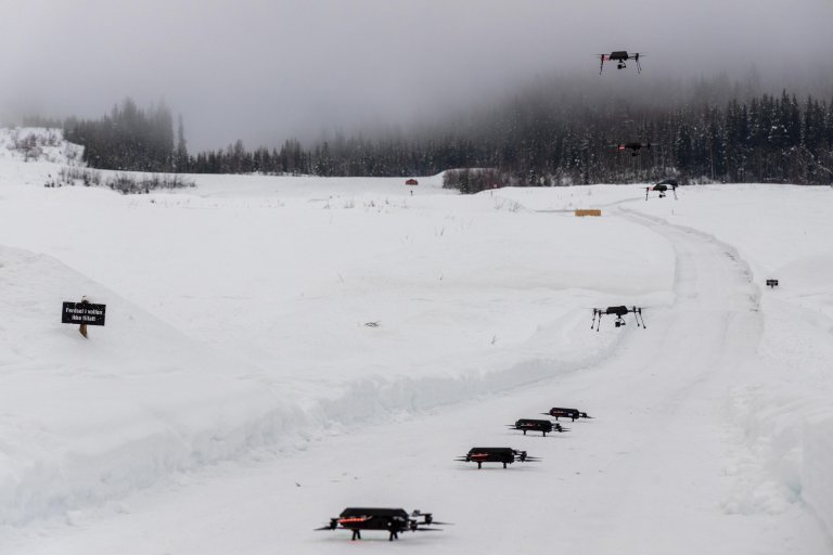 Dronesverm i vinterlandskap. Noen droner står på bakken, andre flyr i luften.