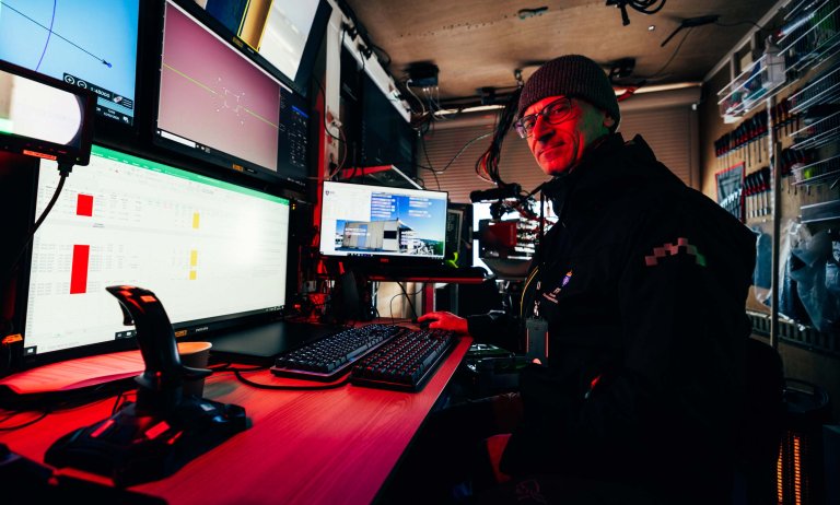 En forsker sitter bak mange skjermer og flere tastatur.