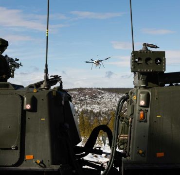En soldat på et kjøretøy sikter på en drone med et våpen.