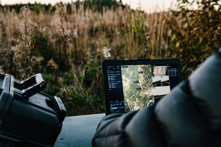 Soldat ser på skjerm med oversikt over dronene i en sverm. Utendørs. Høst.