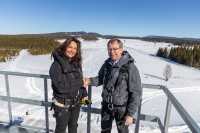 Direktør Birgitte Engebretsen i Telenor Norge og FFI-direktør Kenneth Ruud utveksler håndtrykk i toppen av en mast. Strålende blå himmel og norsk vinterlandskap i bakgrunnen.