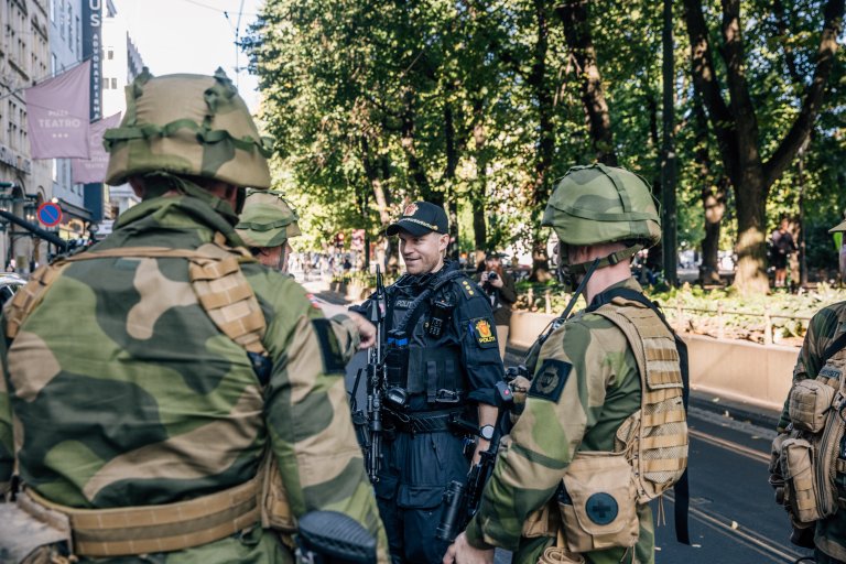 Tre heimevernssoldater og en politimann snakker sammen på gaten i spikersuppa i Oslo sentrum.