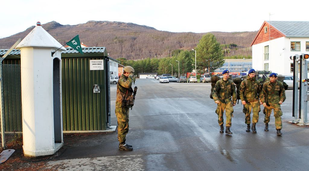 En vakt hilser tre soldater på vei ut fra Maukstadmoen leir.