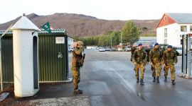 En vakt hilser tre soldater på vei ut fra Maukstadmoen leir.